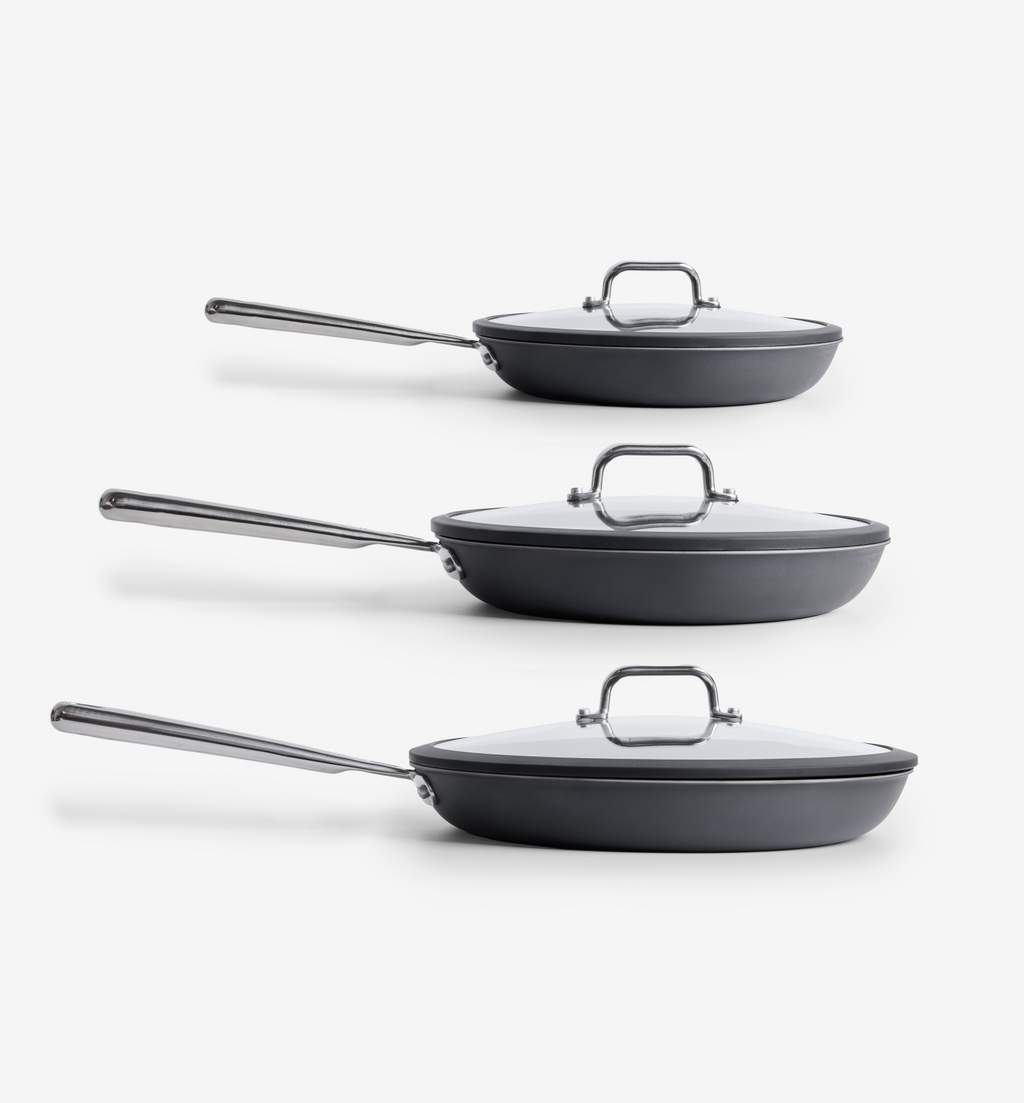 Set of three hard-anodized nonstick frying pans with glass lids and stainless steel handles in graduated sizes